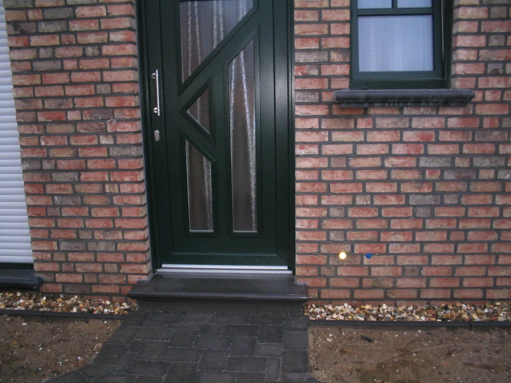 Beton-Stufe vor dunkelgrüner Haustür mit angrenzendem Fenster