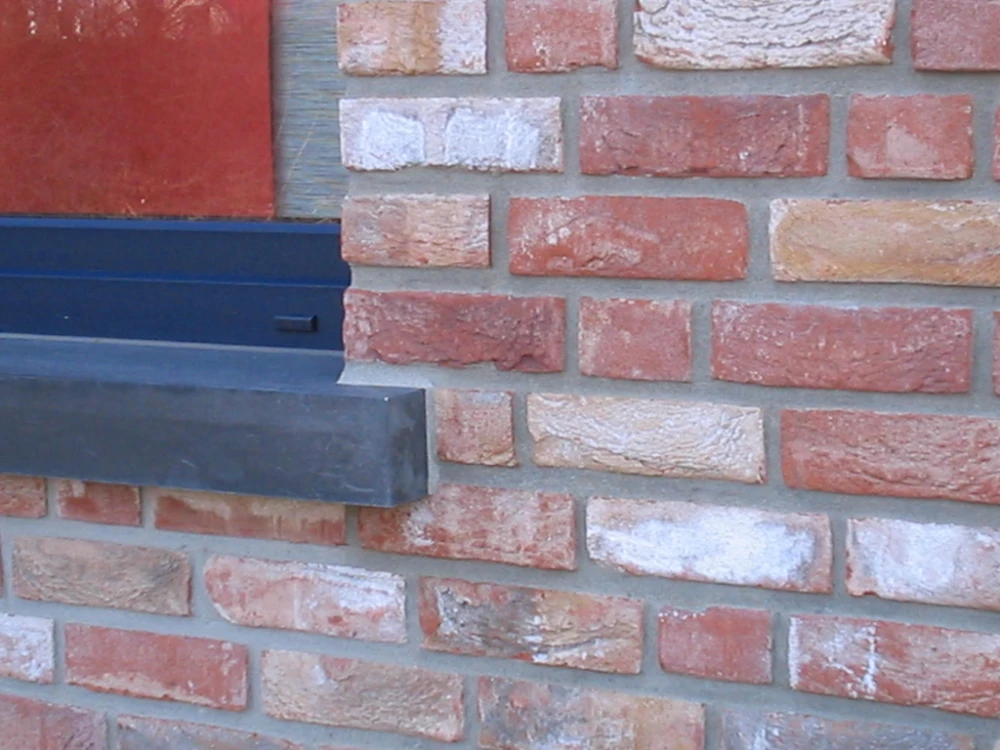 Dunkle Beton-Fensterbank unter Fenster in gemischter Klinkerfassade