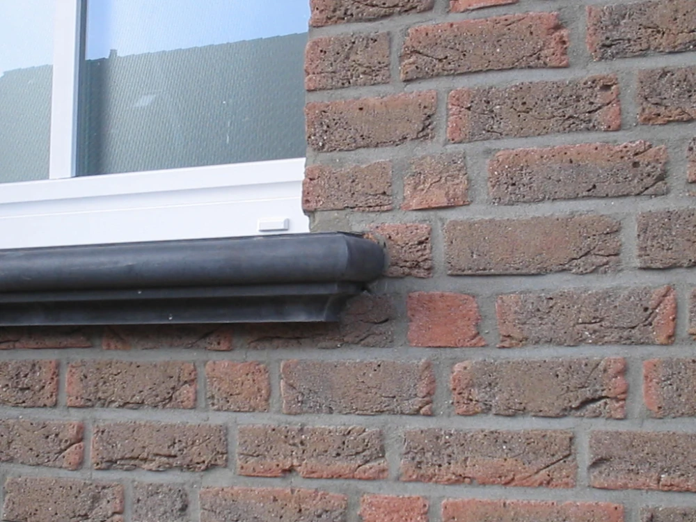 Seitenansicht einer profilierten dunkelgrauen Beton-Fensterbank an Klinkerfassade